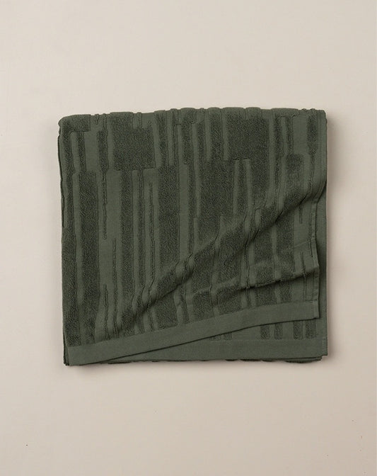 Folded green towel on a beige background