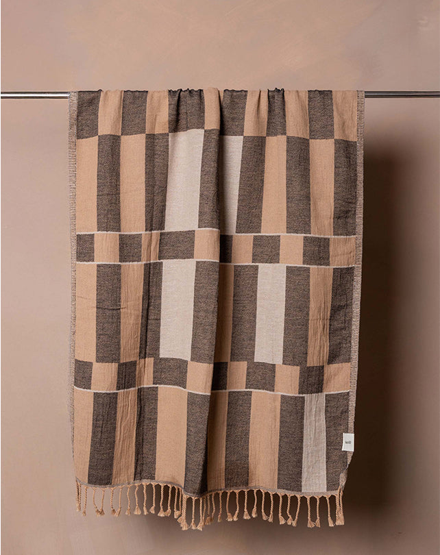 Plaid blanket with brown and beige pattern on a plain background