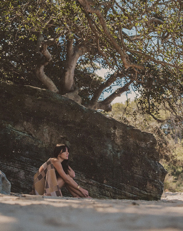 Person sitting under a large tree with a rocky outcrop