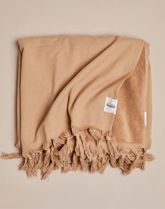 Beige towel with tassels on a beige background