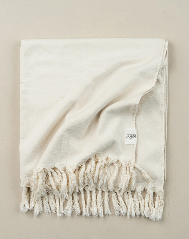 Beige throw blanket with fringes on a beige background