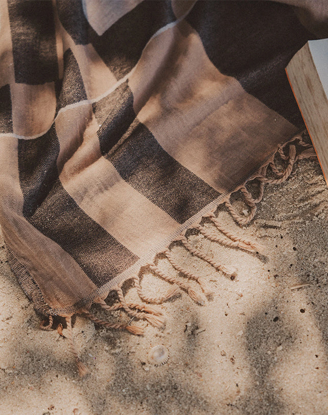 Striped towel with fringes on a sandy surface