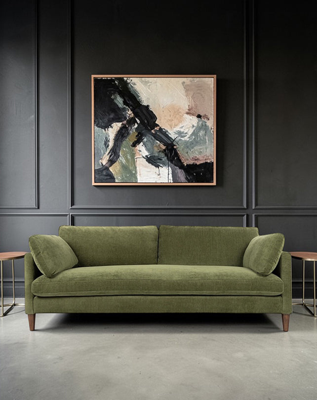 Green sofa in a room with a dark wall and abstract painting