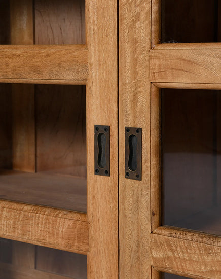 Close-up of a wooden cabinet with glass panels and metal handles.