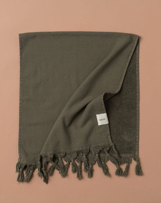 Dark green towel with tassels on a brown background
